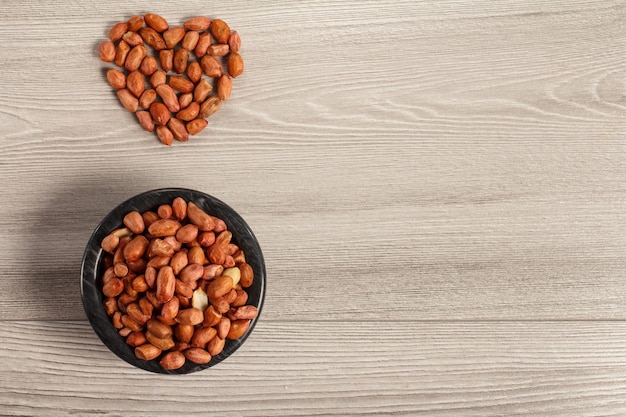 Black bowl with peanuts and heart shaped peanuts beside it