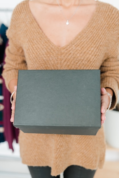 Black box held by young casual shop assistant or customer in beige pullover