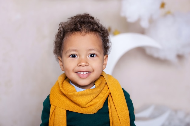 Black boy close up. Portrait of a cheerful smiling Black boy in a yellow scarf. Portrait of a little African American. Black guy. Pensive child. Childhood. child plays in kindergarten. Little boy face