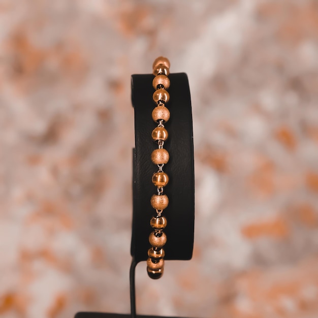 A black bracelet with a gold bead and a black band.