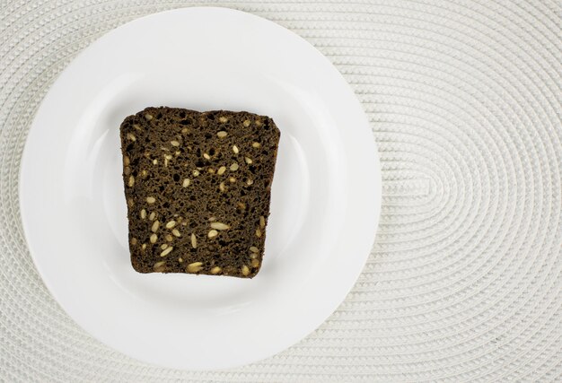 Black bread with seeds on a white plate