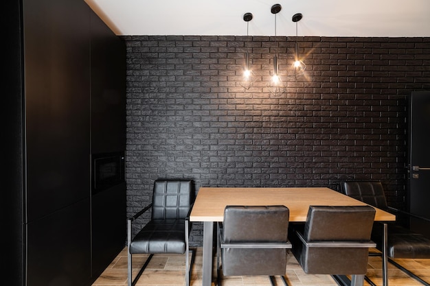 Black brick wall in new kitchen with black chairs and\
table