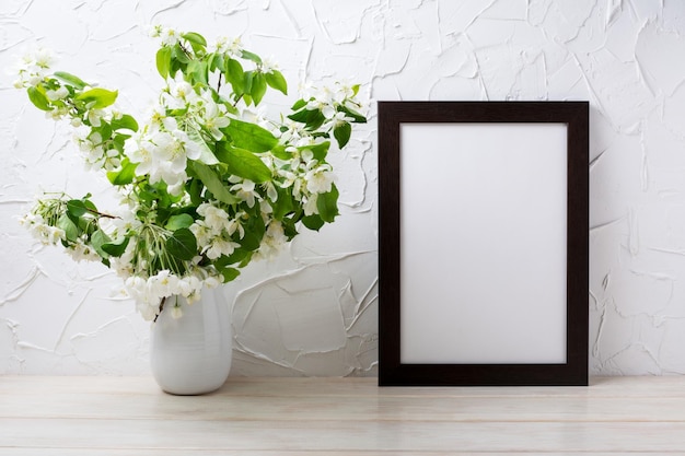 Foto mockup di cornice marrone nero con rami di fiori di melo nel vaso mockup di cornice vuota per il design della presentazione cornice del modello per l'arte moderna