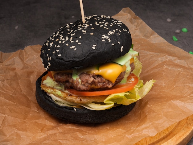 Black burger with chicken and beef, cheddar cheese, tomato. CUCUMBER AND LETTUCE LEAF
