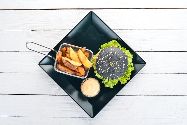 Black burger with meat onion and lettuce On a wooden background Top view Copy space