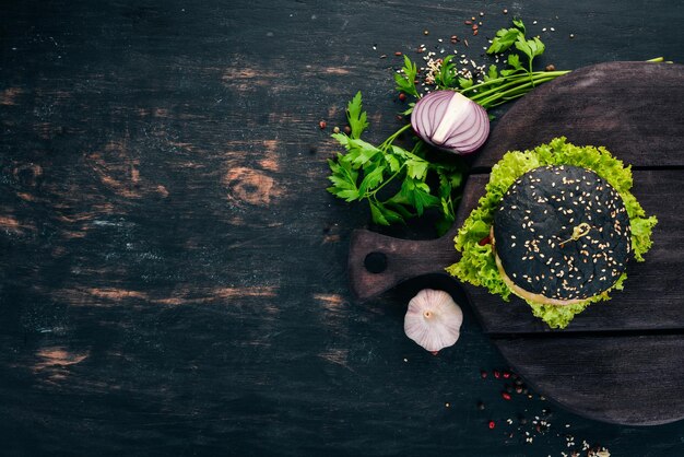 Black burger with meat onion and lettuce On a wooden background Top view Copy space