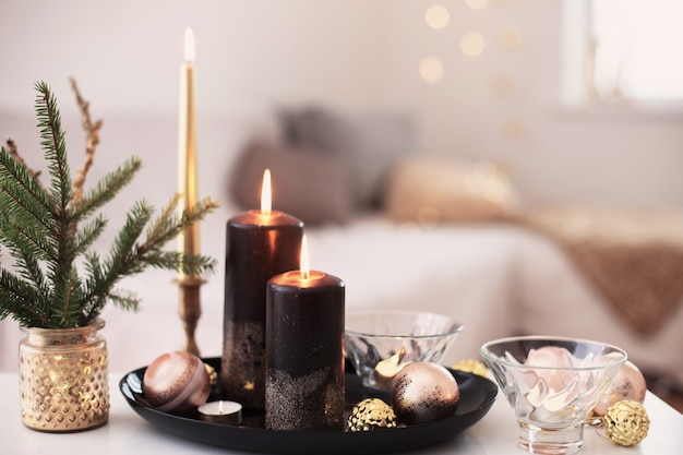 Black burning candles with Christmas balls in white interior