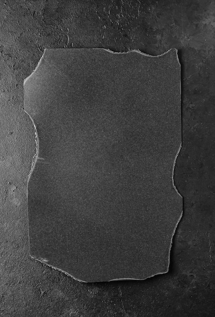 Black burnt paper on a dark concrete background Design elements or portfolio Copy space