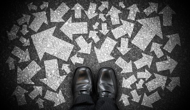 Black business shoes and many chalky arrows in various directions chaos concept