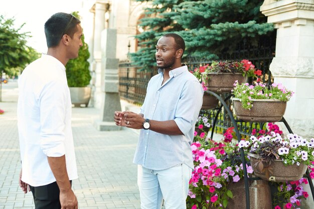 A black businessman is talking in an informal setting with a business partner on a city street