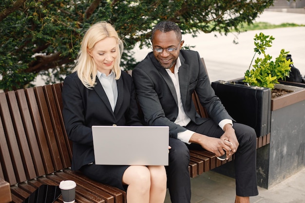 Black businessman sitting on a bench and talk with caucasian woman