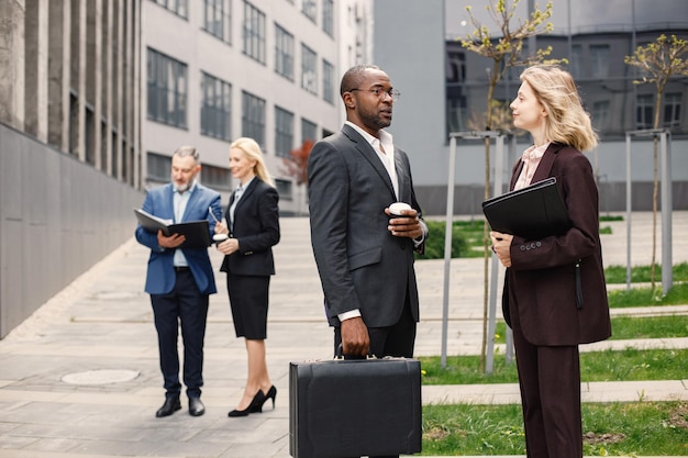 Black businessman standing and talk with caucasian woman in front of modern office