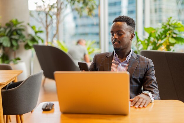 Uomo d'affari nero che utilizza il computer portatile alla caffetteria