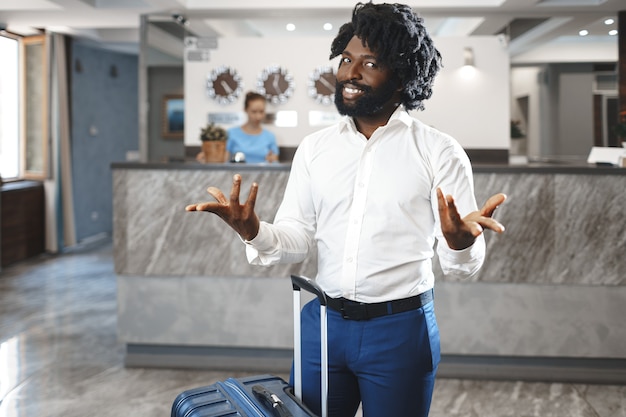 Black businessman with packed luggage standing in hotel lobby