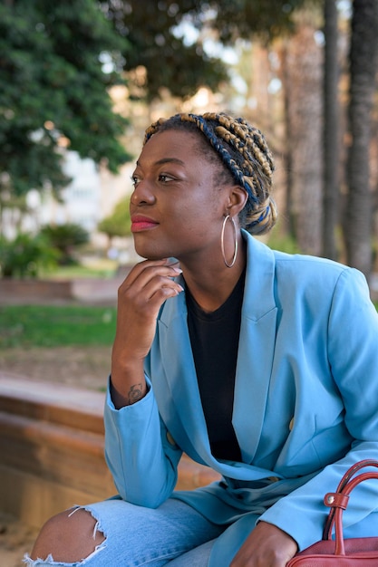 Black businesswoman poses sitting in a park with a blue suit