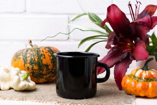 Black campfire enamel mug mockup with pumpkin and red lily