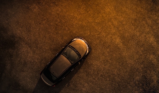 Black car on parking lot concrete evening time aerial view 