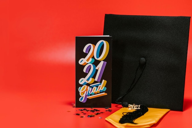 Black Card and Graduation Cap on Red Background Stock Photo