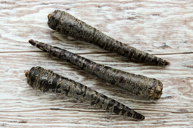 Black carrots on a light wooden table