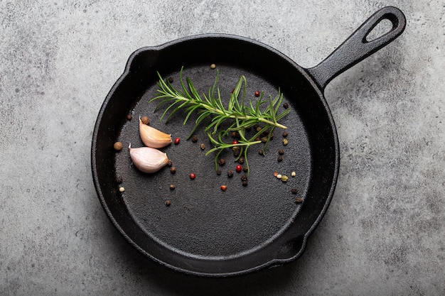 Black cast iron frying pan with rosemary garlic pepper top view