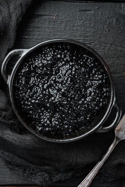 Black Caviar bowl, on black wooden table table, top view flat lay