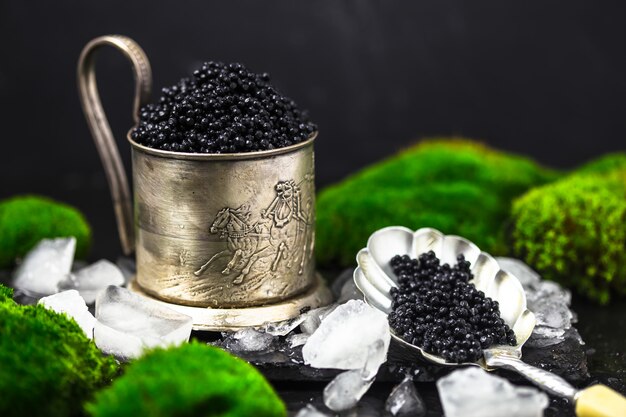 Black Caviar in a bowl. High quality real natural sturgeon black caviar close-up. Delicatessen. Texture of expensive luxury caviar square dish on black