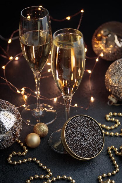 Foto caviale nero in barattolo e bicchiere di champagne con decorazioni natalizie