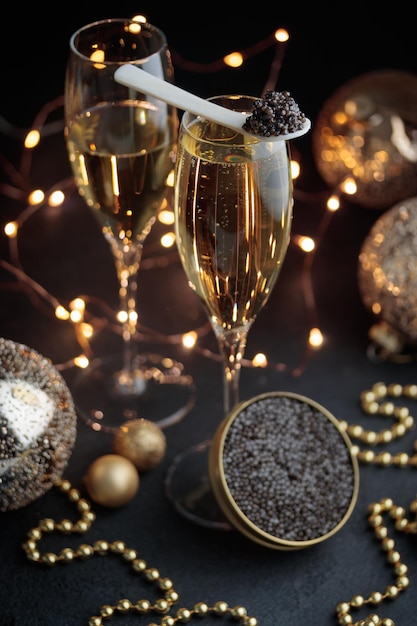 Foto caviale nero in un cucchiaio di perla madre e lar con un bicchiere di champagne con decorazione natalizia verticale