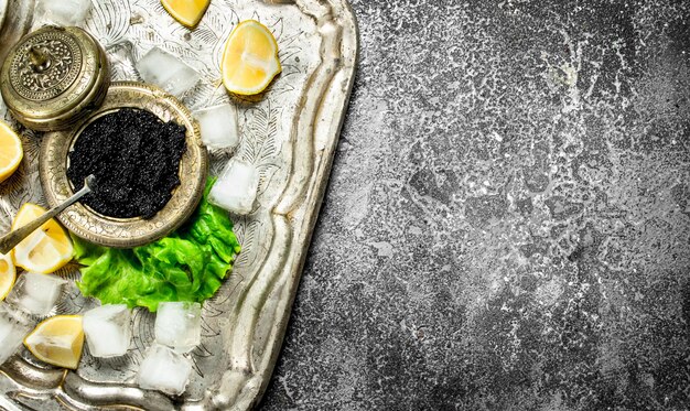 black caviar on the old tray of ice. On rustic background .