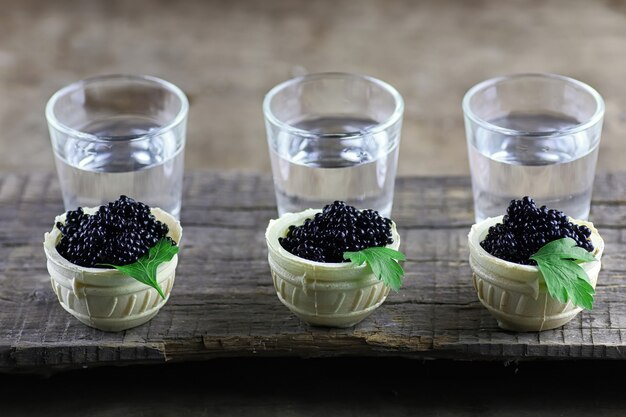 Black caviar in the portion on a wooden background