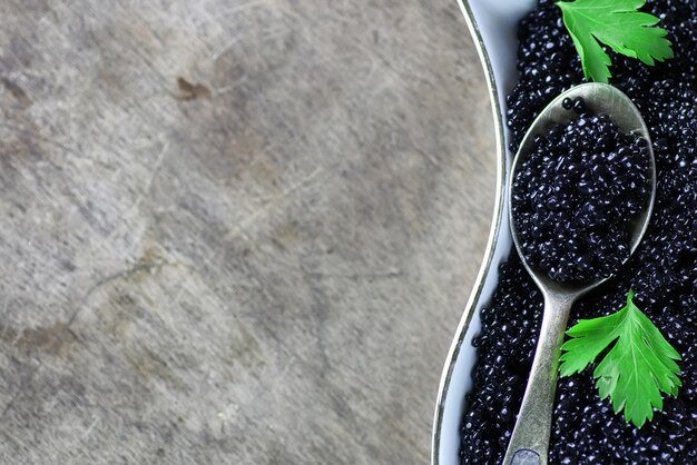 Black caviar in the portion on a wooden background