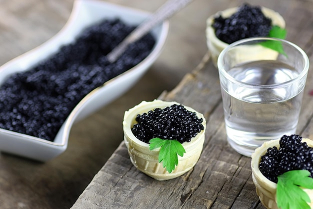 Black caviar in the portion on a wooden background