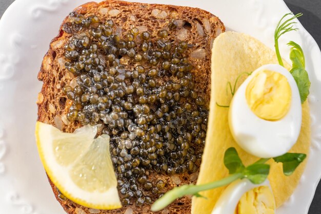 Black caviar on a sandwich with eggs lemon greenery