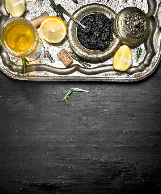 Black caviar with white wine on the old tray.