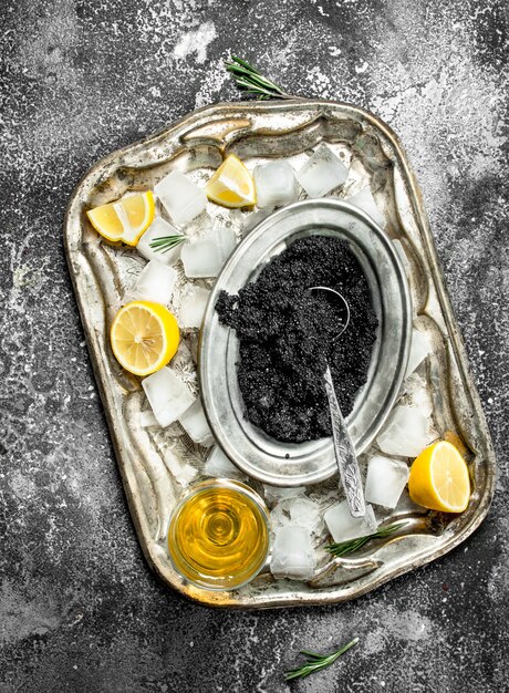 Black caviar with white wine and slices of lemon. On rustic background .