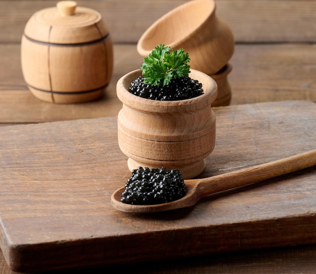 Black caviar in a wooden plate on the table