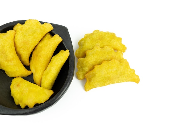 Black ceramic bowl with Colombian empanadas on white background.