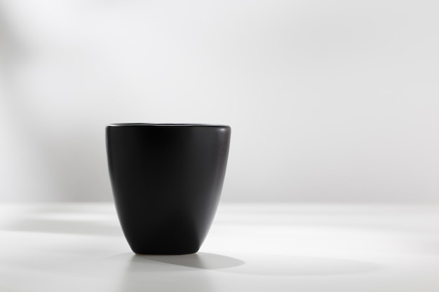 Tazza in ceramica nera su un tavolo bianco