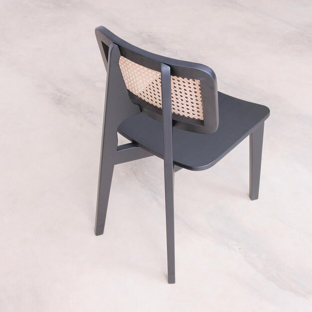 A black chair with a brown pattern on the back sits on a white floor