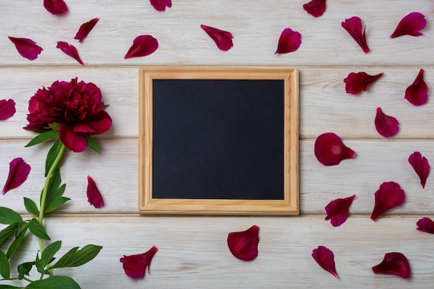 Black chalkboard wooden square frame mockup with burgundy peony and petals Empty blackboard frame mock up for presentation design Template black felt letter board framing for modern art