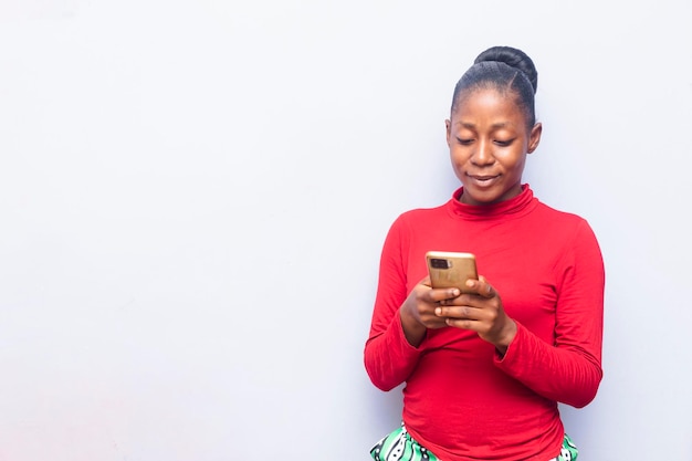 Черная очаровательная африканская девушка, стоящая и держащая мобильный телефон для ввода сообщений