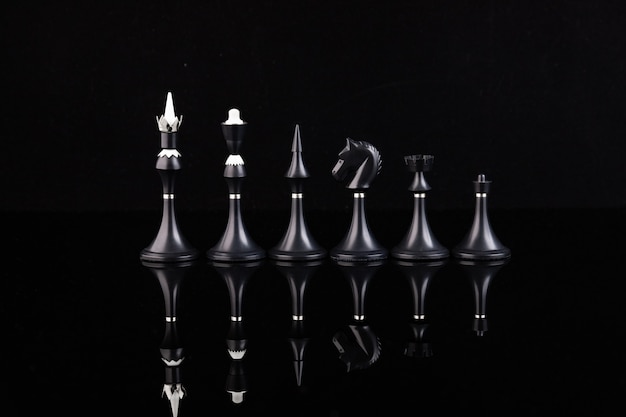 Black chess pieces on a reflective surface. Business concept. Game, strategy, wisdom, determination.