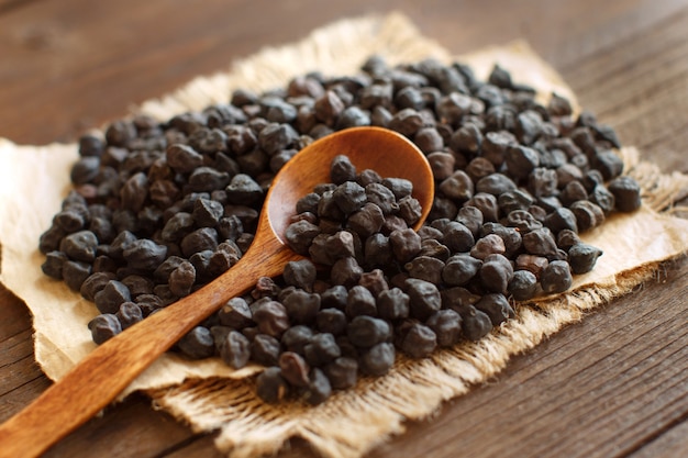 Black Chickpea with a spoon on a wooden table close up