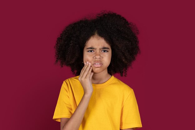 Black child in pain touching cheek isolated on colorful background