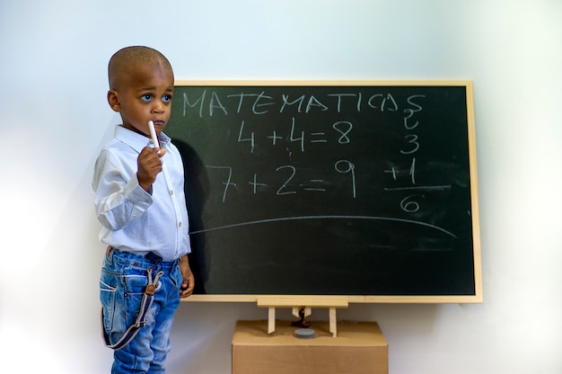 Un bambino nero che scrive su una lavagna