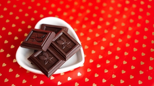 Black chocolate in a heart shaped plate on red