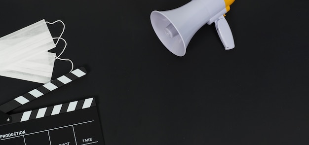 Black clapper board or movie slate and face mask ,megaphone on black background.it use in video production and movie industry.