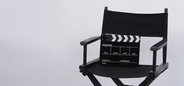 Photo black clapper board or movie slate with director chair use in video production or movie and cinema industry. it's put on white background.