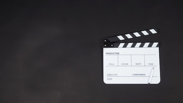 Черная с 'хлопушкой' или хлопковая доска или грифель для кино с ручкой, используемой в производстве видео, кино, киноиндустрии. Наденьте черный фон.