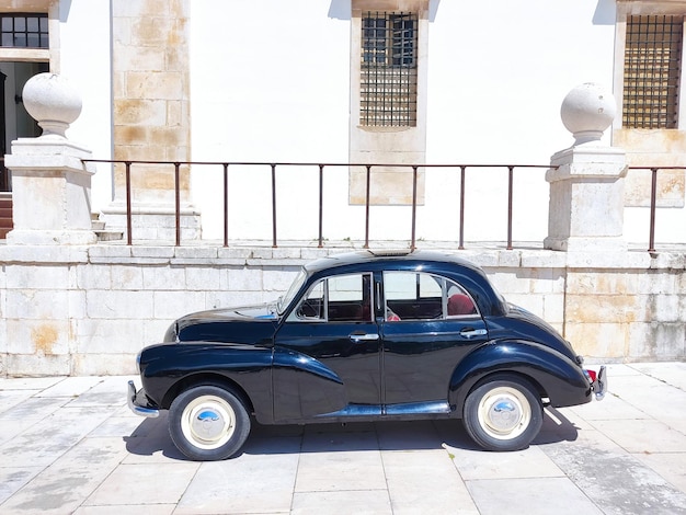 Black classic car on the background of an ancient European monastery Vintage polished restored vehicle wallpaper